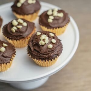 Close-up of chocolate cupcakes with icing and white chocolate chips on a plate.