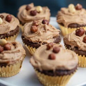 Close-up of homemade chocolate cupcakes topped with hazelnut frosting, perfect dessert.